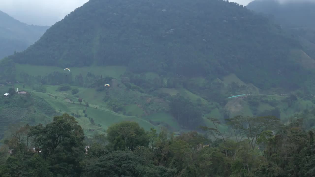 哥伦比亚，在花园村的青山间飞行的滑翔伞视频素材