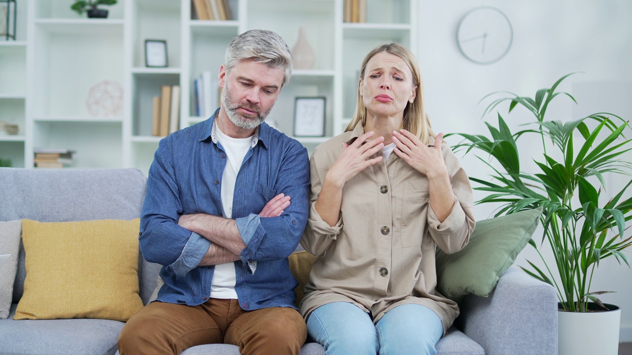 摄像头的观点。悲伤的已婚夫妇坐在家里的沙发上与家庭心理学家进行视频通话。视频素材