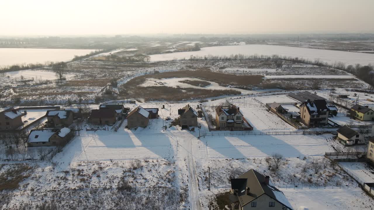 鸟瞰图，在寒冷的冬天，农村郊区的私人住宅被雪覆盖着屋顶视频素材