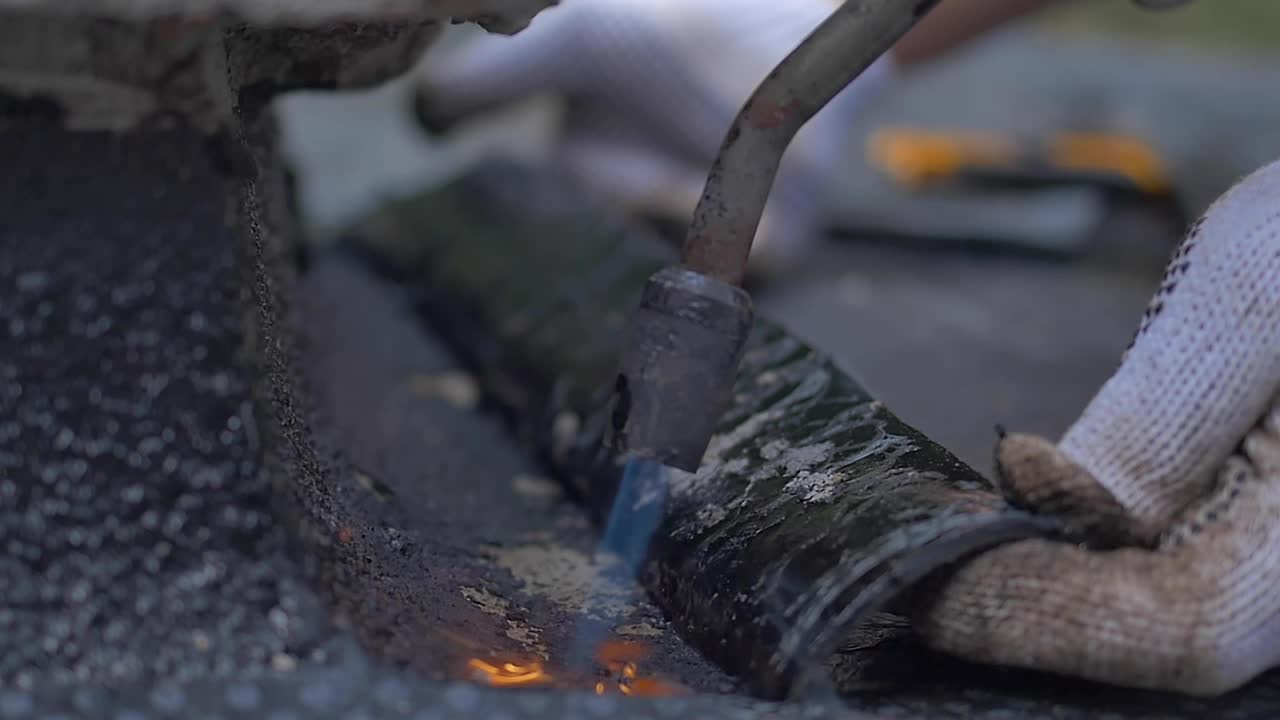 建筑工人在屋顶上密封防水层视频素材