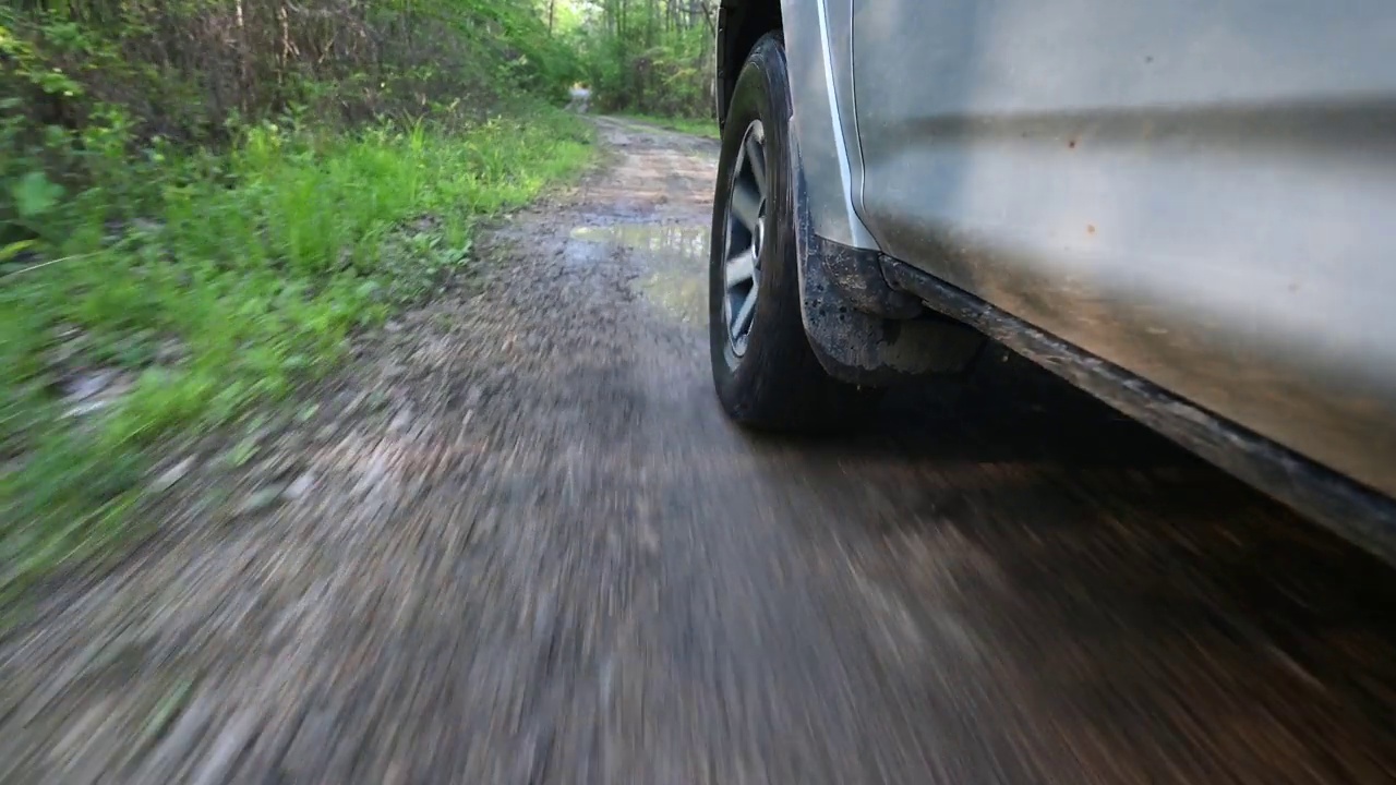 从地面上看，在有水坑的狭窄道路上，4x4越野车正在降落视频素材