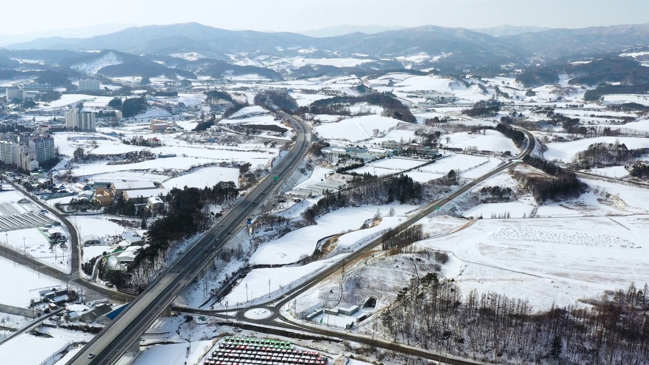 韩国江原道平昌郡大关岭附近的山峦、村庄和道路上的雪景视频素材