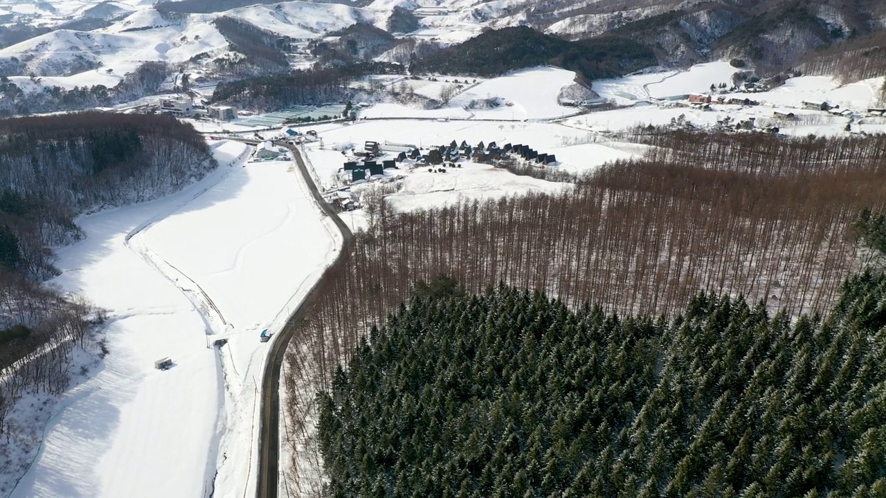 韩国江原道平昌郡大关岭附近的山峦、村庄和道路上的雪景视频素材