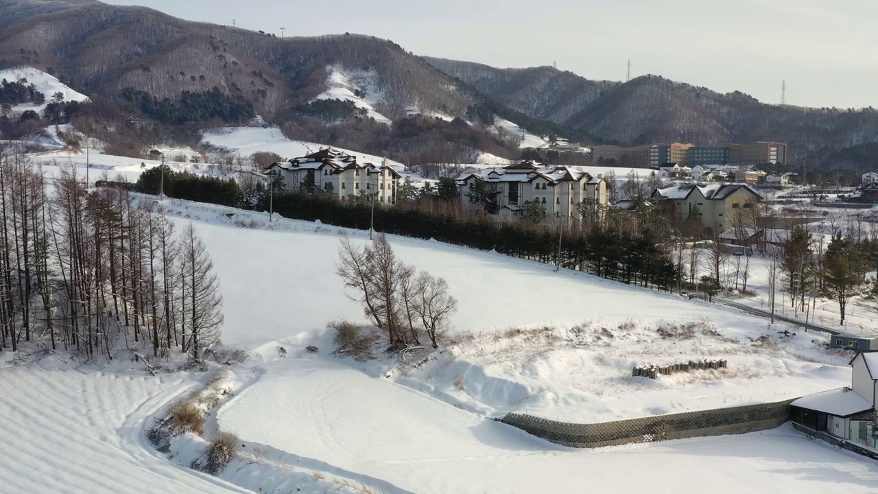 韩国江原道平昌郡大关岭附近的山峦、村庄和道路上的雪景视频素材