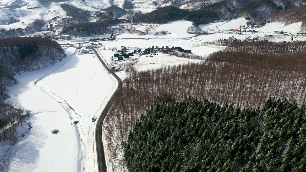 韩国江原道平昌郡大关岭附近的山峦、村庄和道路上的雪景视频素材