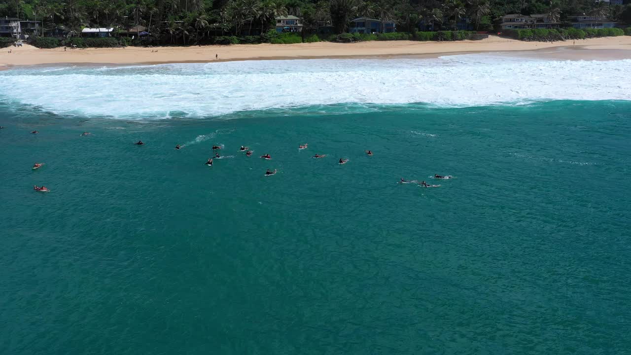 在阳光明媚的一天，冲浪者在夏威夷瓦胡岛海滩上用冲浪板游泳的航拍镜头视频素材