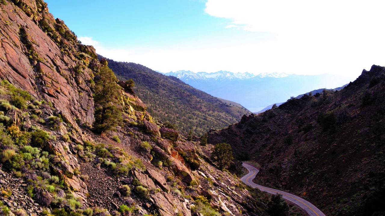 空中拍摄的汽车在道路上移动穿过岩层，无人机在山脉中向后飞行-猛犸湖，加利福尼亚视频素材