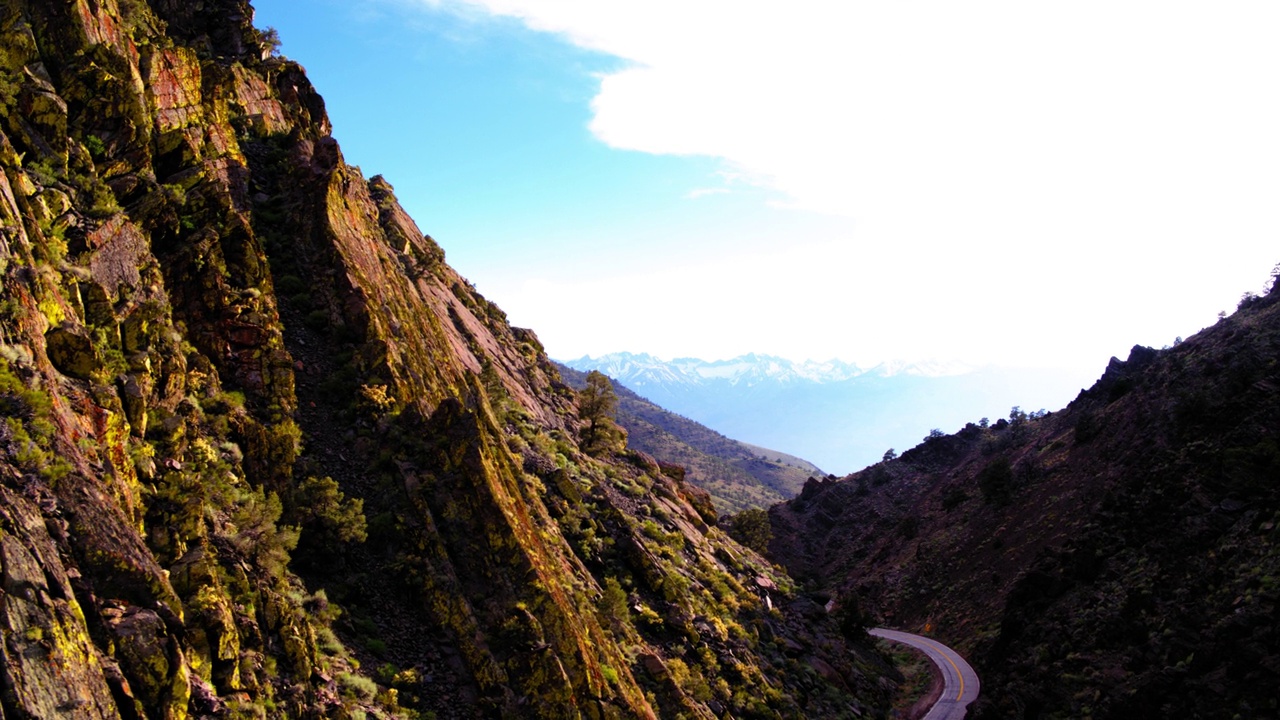 空中平移拍摄的道路通过山谷对天空，无人机飞行岩层在阳光明媚的日子-猛犸湖，加利福尼亚视频素材