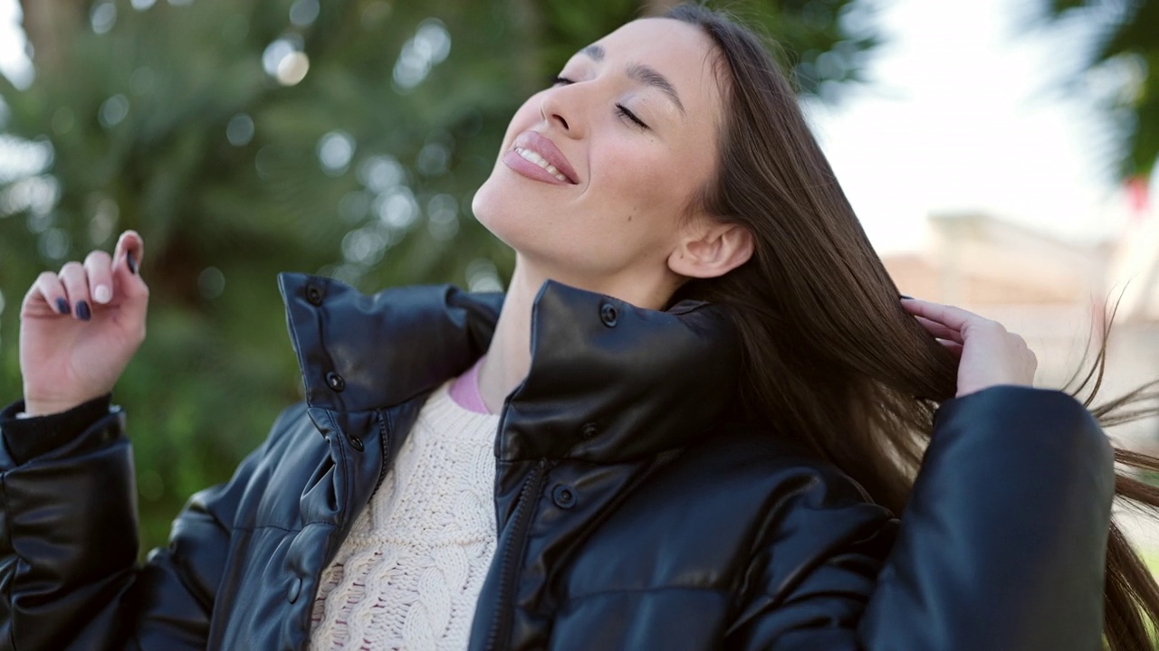 年轻美丽的西班牙女子微笑自信地在公园用手梳理头发视频素材