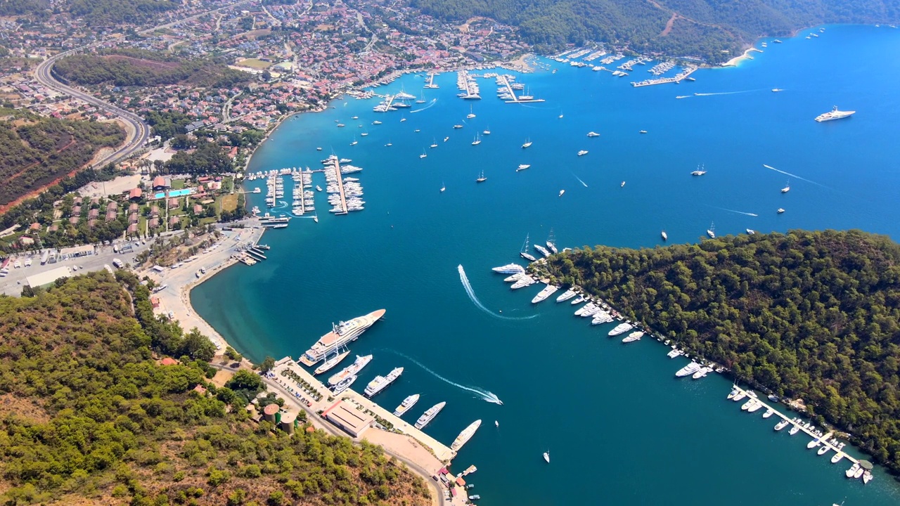 Aerial drone view of the bustling Göcek Marina, located in the beautiful coastal town of Muğla, Turkey, captured by a drone showcasing the vibrant harbor and surrounding landscape.视频素材