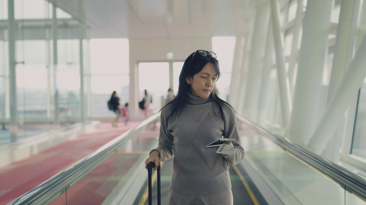 在候机楼准备继续旅行的妇女。她站在人行道上，手里拿着护照视频素材