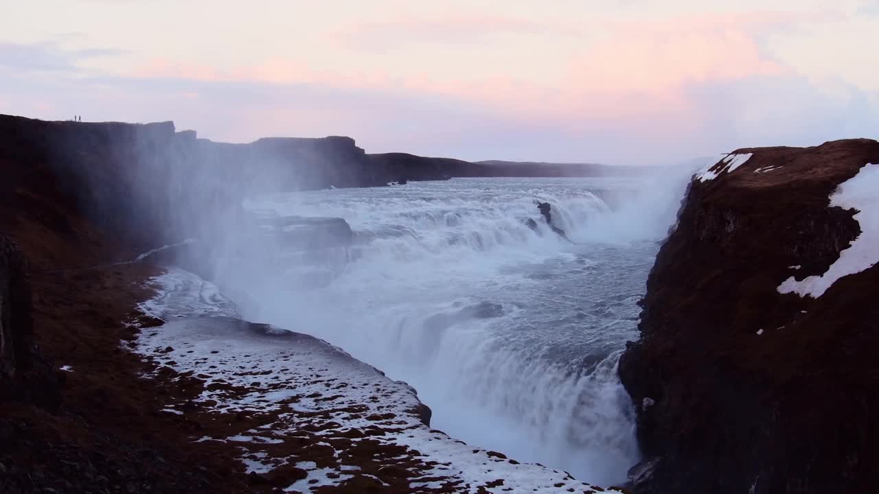 冰岛的Gullfoss瀑布，电影般美丽雄伟的冬季瀑布被冰雪覆盖。缓慢的运动。日落的天空视频素材