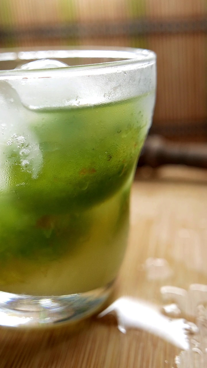 Cocktail to go. Caipirinha glass close-up shot. Brazilian caipirinha glass ready to drink. Caipirinha drink to go.  Preparing a caipirinha. Making a caipirinha (sugar, ice, cachaça, lemon). Caipira drink on the table. Glass of caipirinha close-up angle视频素材