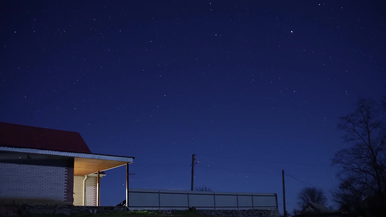 夜空中星星的运动，背景是一座村庄的房子视频素材