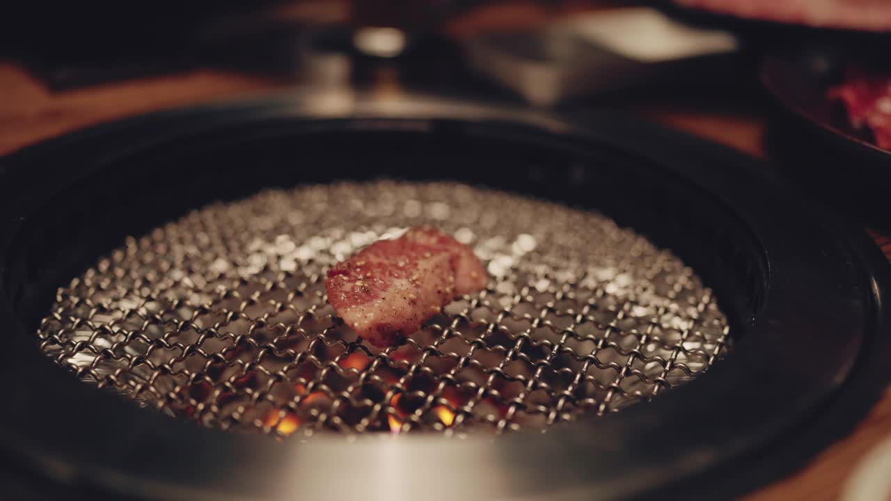 近看日式烧肉。
在日本餐馆的木炭烤架上切成薄片的多汁的新鲜烤牛肉。视频素材