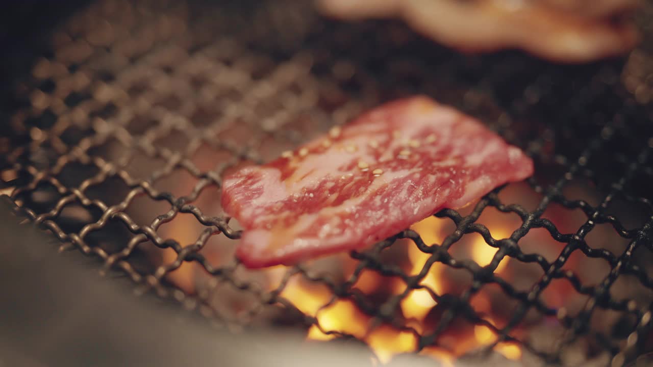 近距离烧烤在日式烧饼店的木炭烤架上烤新鲜多汁的牛肉片。视频素材