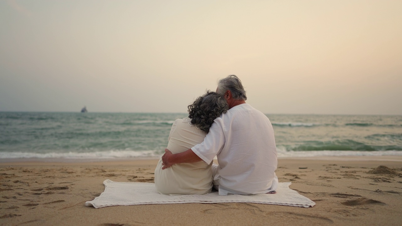 4K亚洲老年夫妇在夏日日落的海滩上一起休息。视频素材