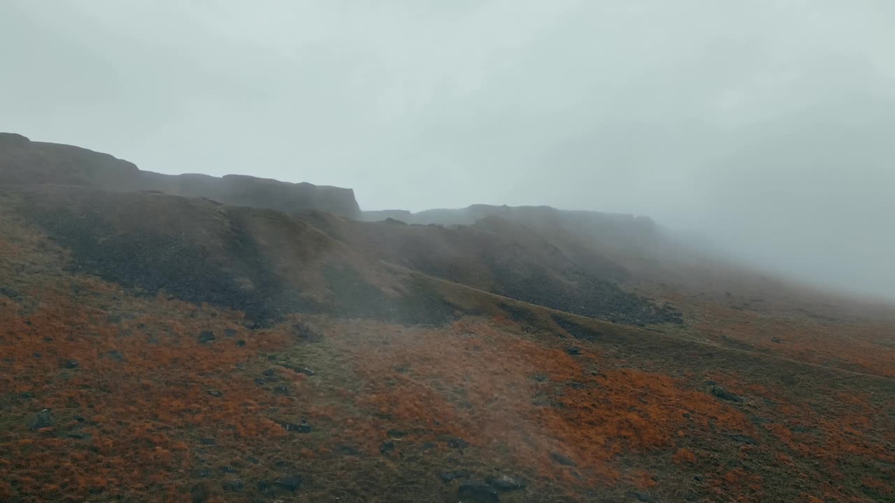 在雾蒙蒙的早晨和沼地上，无人机在迷雾后面的岩石山丘上拍摄的镜头视频素材