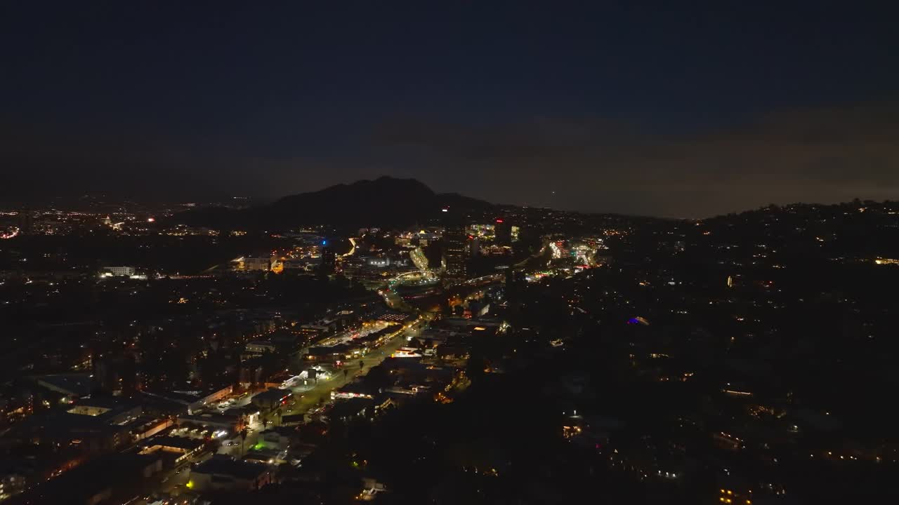 夜城中灯火通明的林荫大道和繁忙的高速公路的航拍画面。群山的剪影映衬着黑暗的天空。洛杉矶，加利福尼亚，美国视频素材