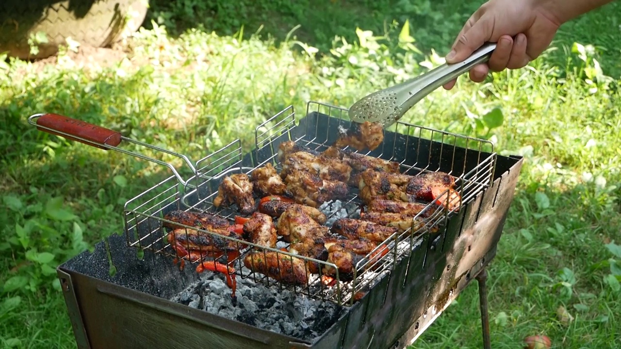 在烤架上烤着。户外烤架上的炸鸡肉和西红柿。视频素材