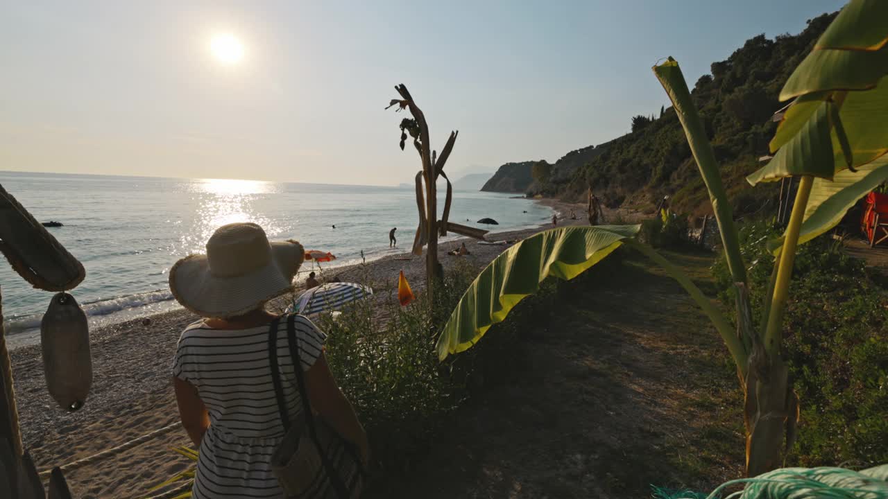 戴着帽子的女人在阳光明媚的日子里欣赏美丽的海滩视频素材