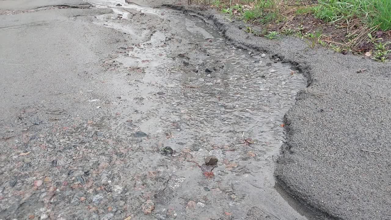 倾盆大雨中河水溢出沥青路面视频素材