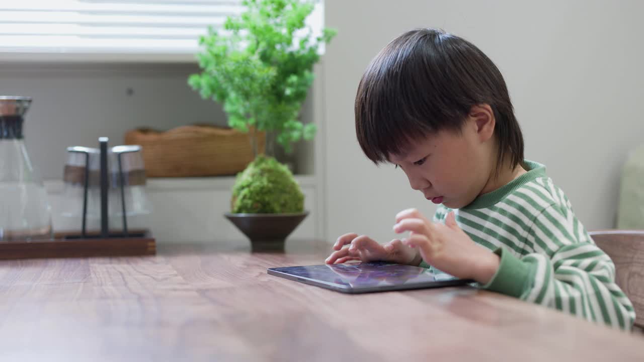 学龄前儿童在餐厅用数码平板电脑玩游戏视频素材