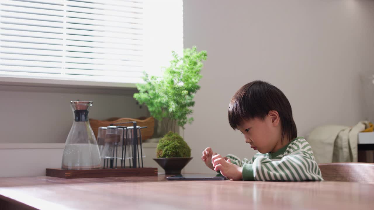 学龄前儿童在餐厅用数码平板电脑玩游戏视频素材