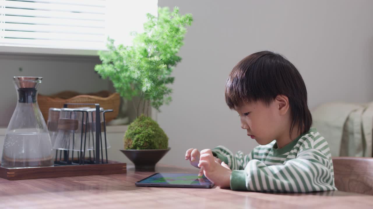 在餐厅里，一个孩子正在用平板电脑玩游戏视频素材