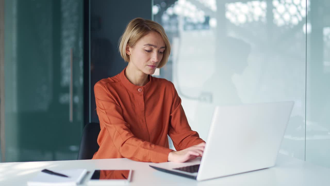 悲伤的年轻金发女子在现代办公室的办公桌前工作时遭受胃痛。视频素材