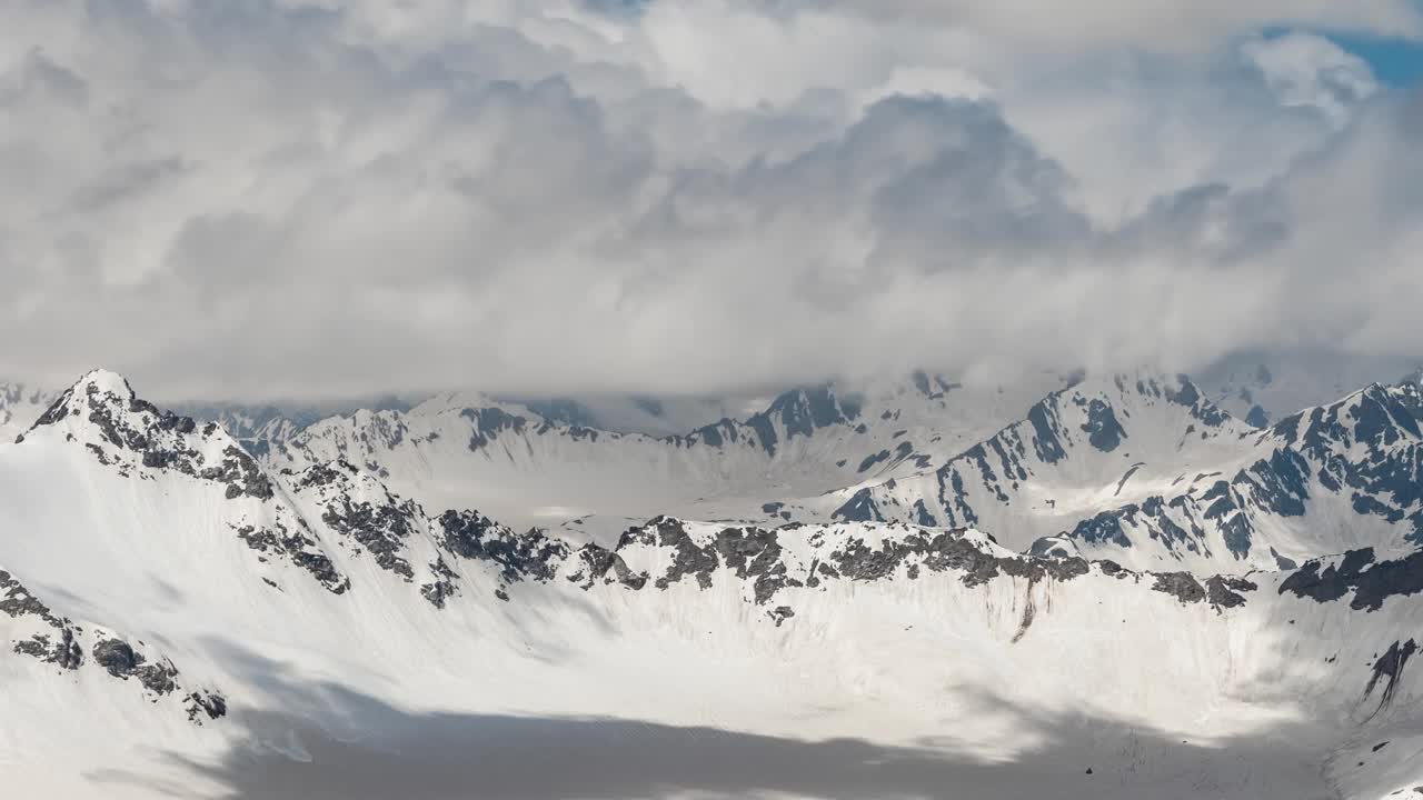 空中飞行穿过山云，飞越美丽的雪峰和冰川。视频素材