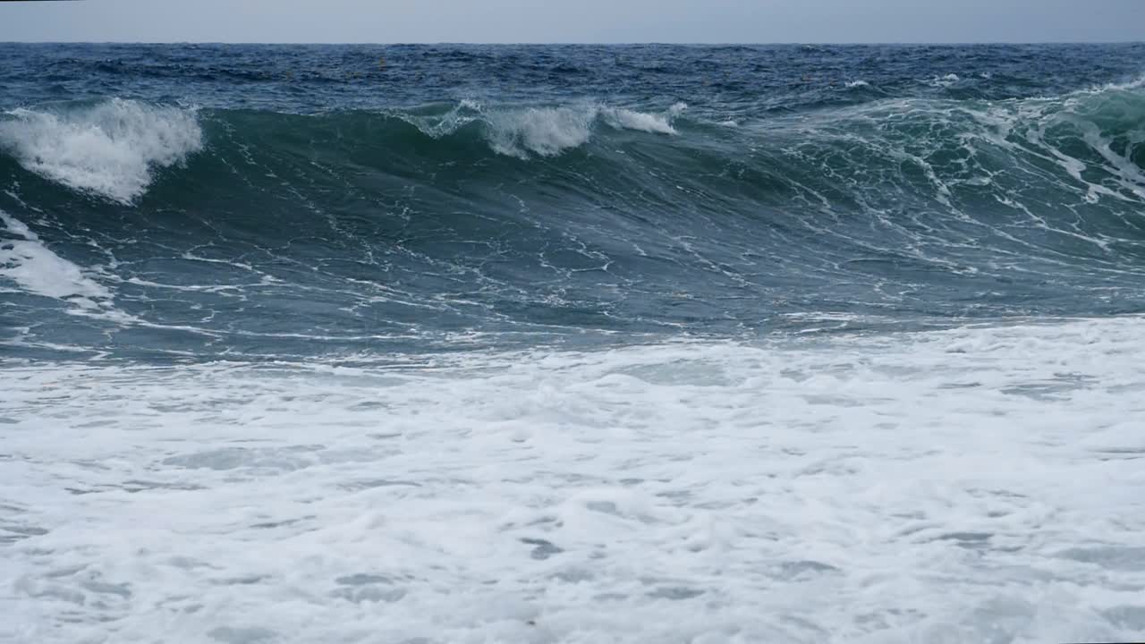 风暴中海浪的慢镜头。巨大的风浪卷向覆盖着白色泡沫的海岸。水元素浩瀚而强大视频素材