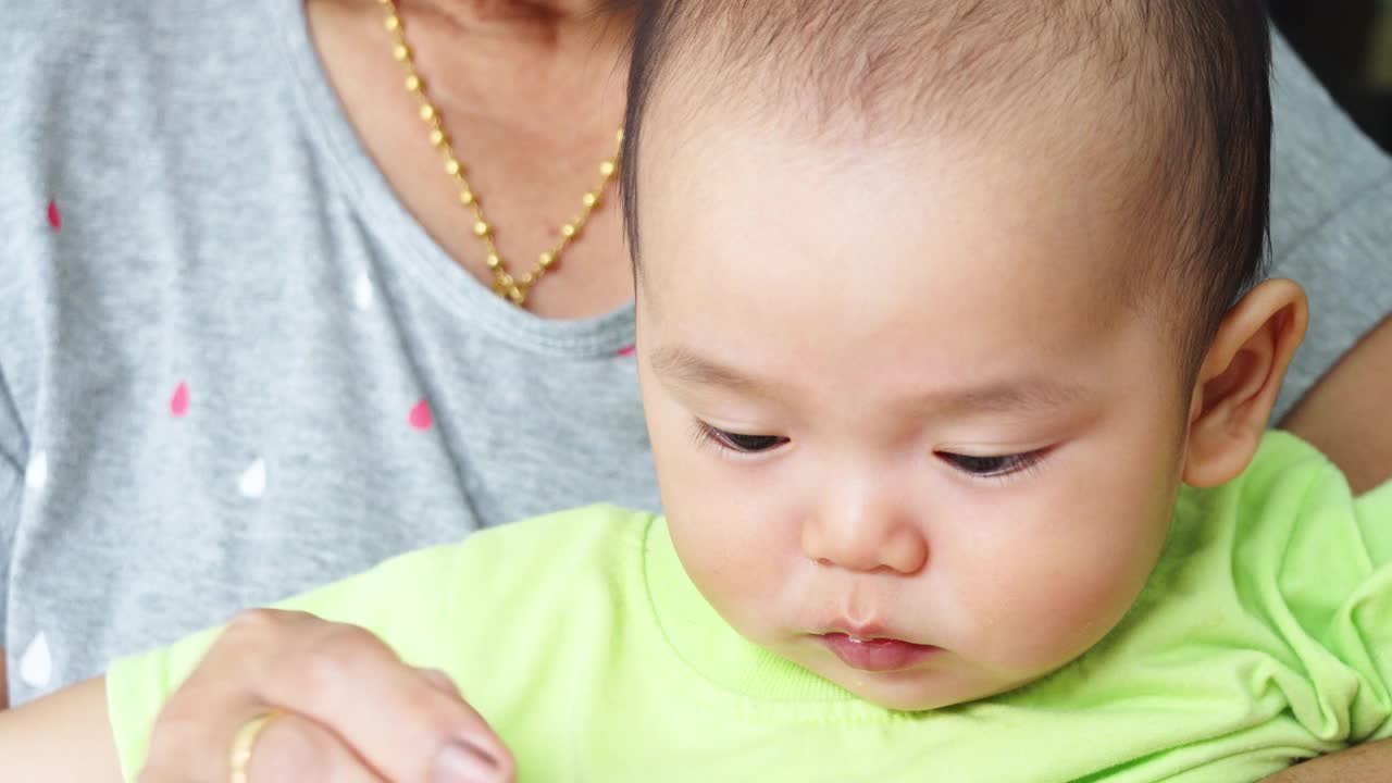 特写亚洲婴儿喂吃食物的脸。视频下载