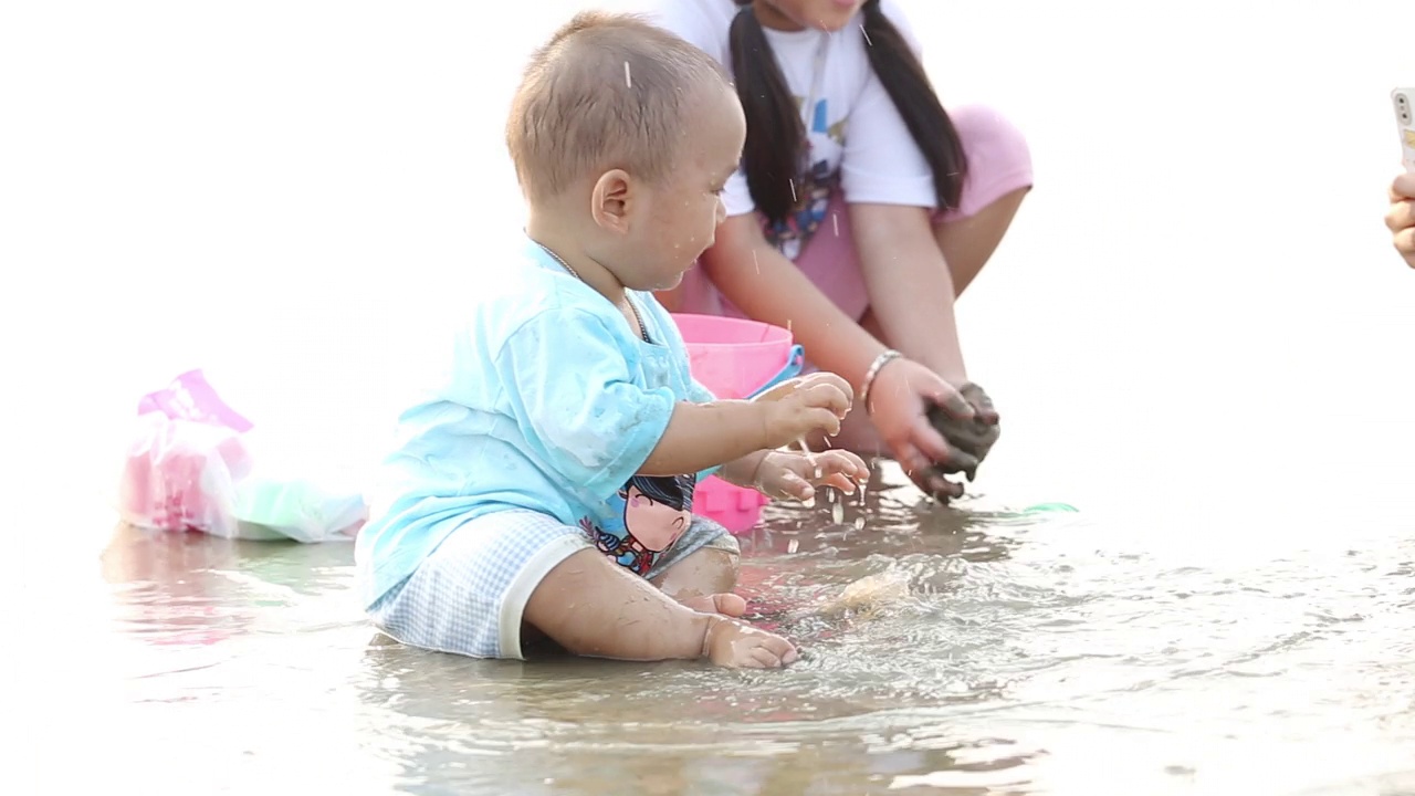 亚洲姐姐和哥哥在沙滩上玩沙子。视频下载