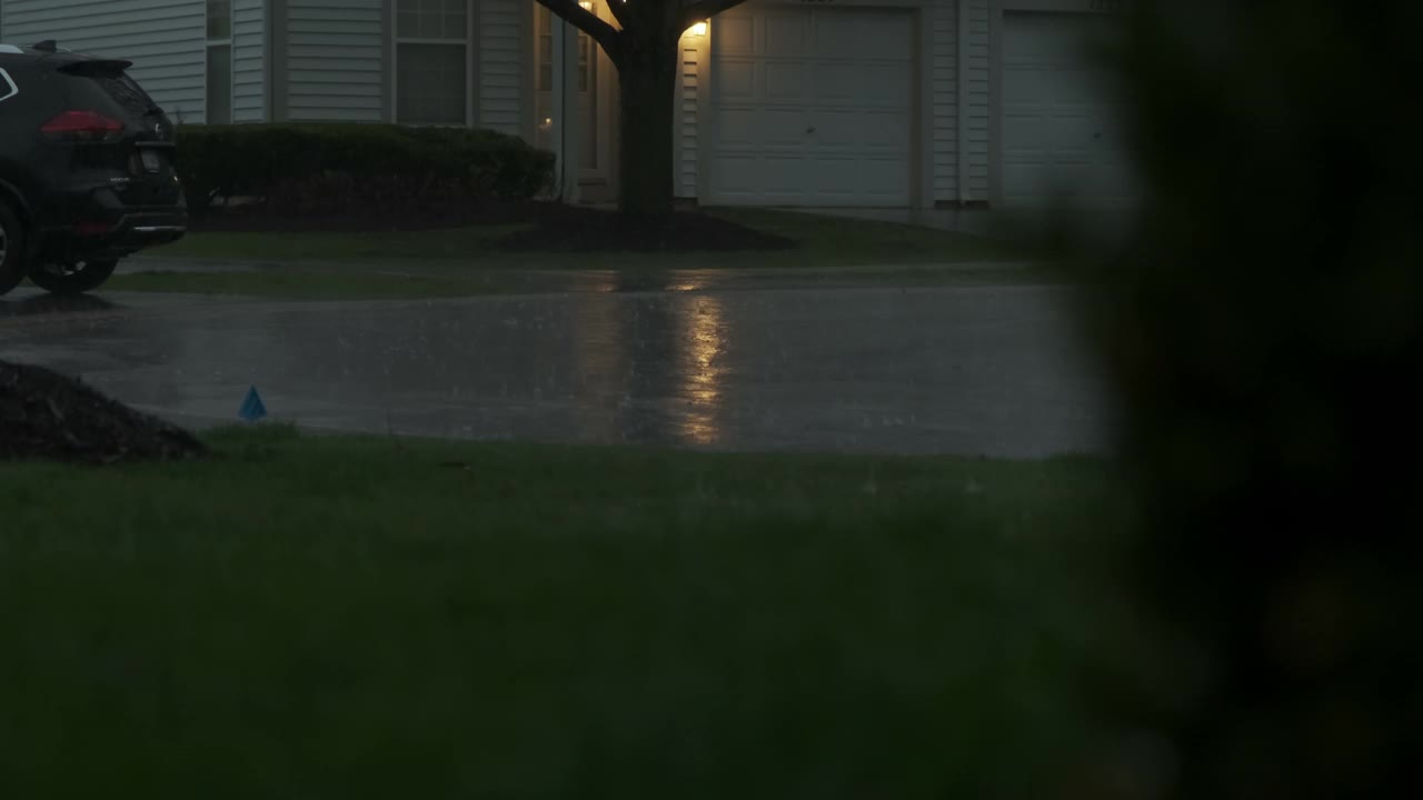 暴雨伴随着闪电，雨点落下，闪电淹没了郊区的街道。慢镜头视频素材