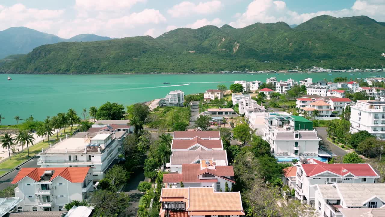 空中无人机拍摄的美丽的热带山谷在山脉和城市之间。太阳的光线穿透云层。夕阳的余晖照在树冠上。4 k视频素材