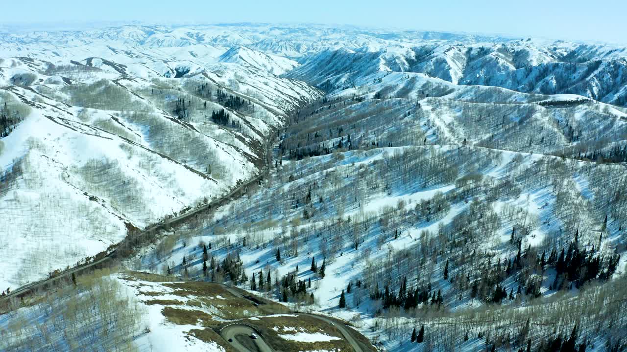 空中无人机俯视图自然冬季景观蛇形公路汽车交通丘陵地形自然山谷。缓慢飞行柏油路转弯通过弯道车辆在山区视频素材