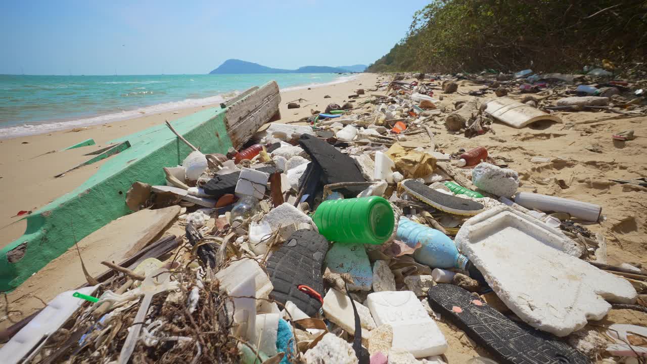 大量的塑料碎片被海浪抛到热带沙滩上。视频素材