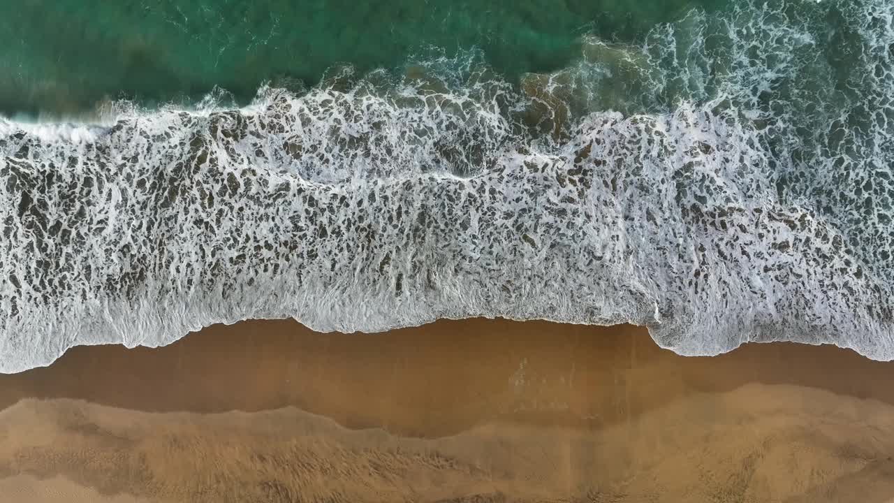 空中俯瞰沙滩和海浪。大海或海浪带着白色的浪花。在加那利群岛，无人机拍摄的冲浪泡沫和黄色空旷的海滩视频素材