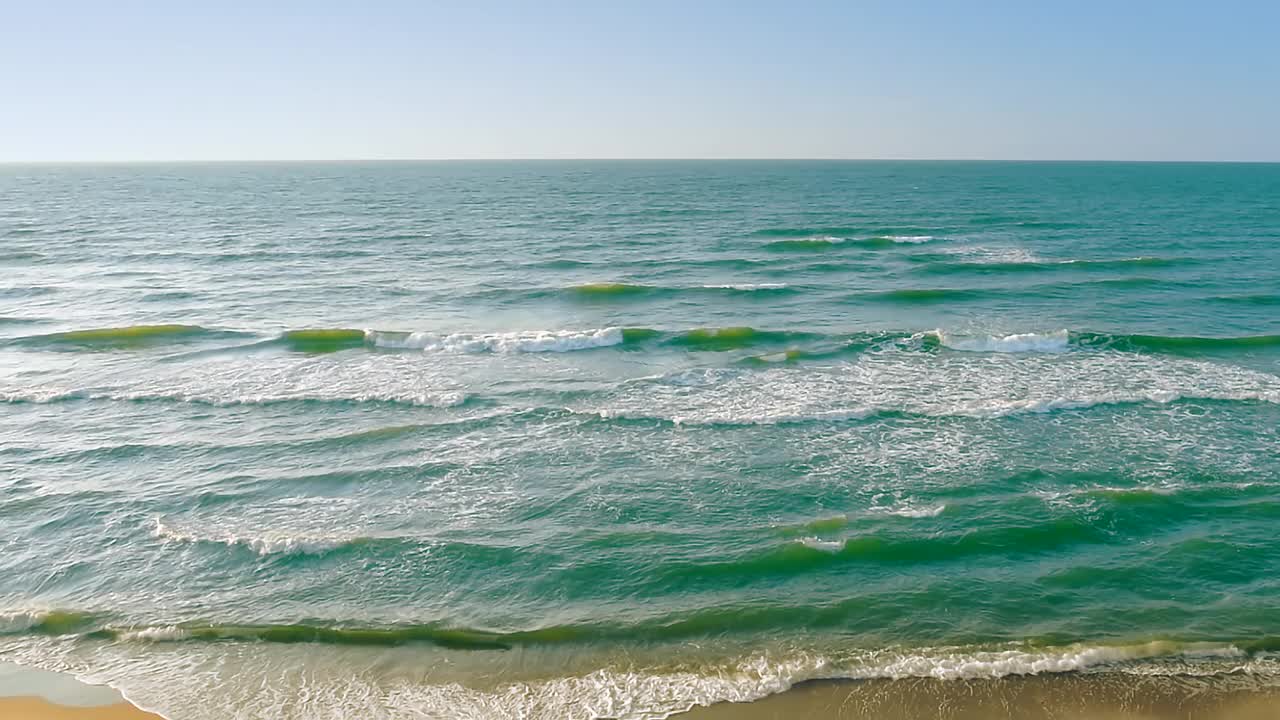 海浪在蓝色阳光明媚的天空背景，广角镜头，平移，实时，高清。ProRes 422 HQ。视频素材