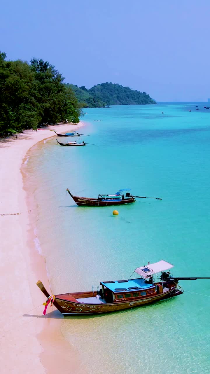 泰国南部的Koh Kradan岛，海滩上有长尾船和蓝绿色的海洋视频素材