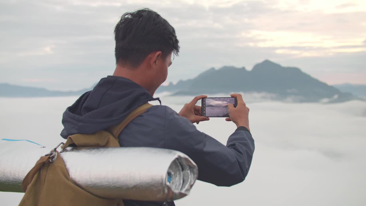 一名亚洲徒步旅行者用智能手机拍下了雾山的全景视频素材