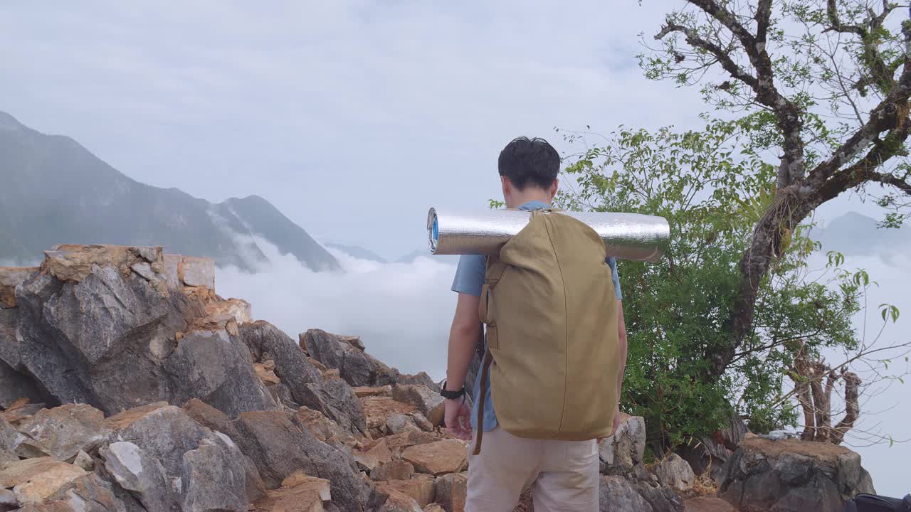 亚洲男性徒步旅行者背着背包在雾山徒步旅行视频素材