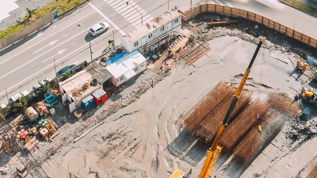 建筑工地的高清超缩鸟瞰图。各种机械和工人在工地上进行维修开发。开发多层住宅楼。繁忙的城市交通。金属结构加工视频素材