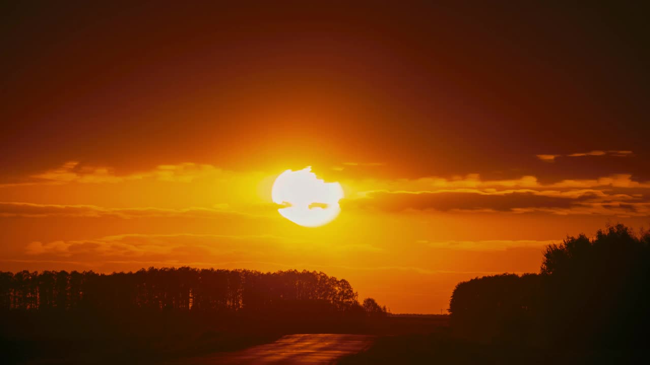 公路旅行概念。4k延时大太阳日落以上的道路景观。戏剧性的日落背景。迷人的汽车轮廓错觉。日落延时，延时在黄色，橙色柔和的颜色视频素材