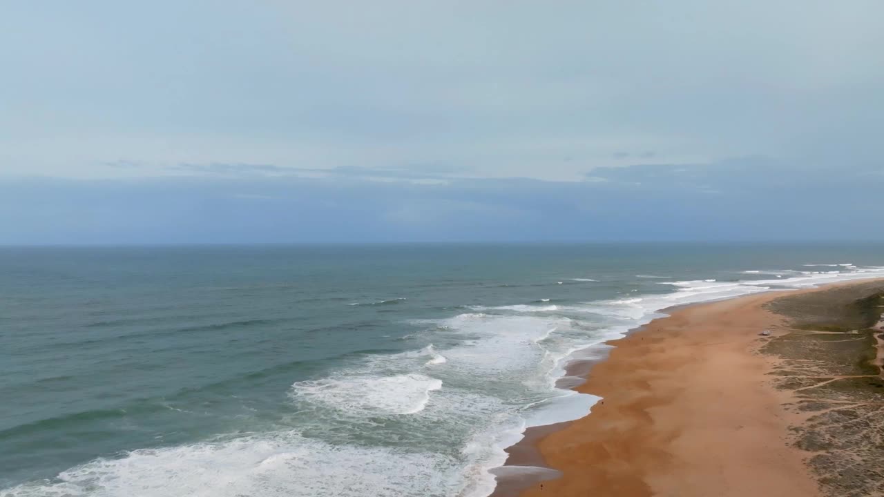 鸟瞰葡萄牙纳扎雷大浪的海滩。两个人在大西洋钓鱼。视频下载