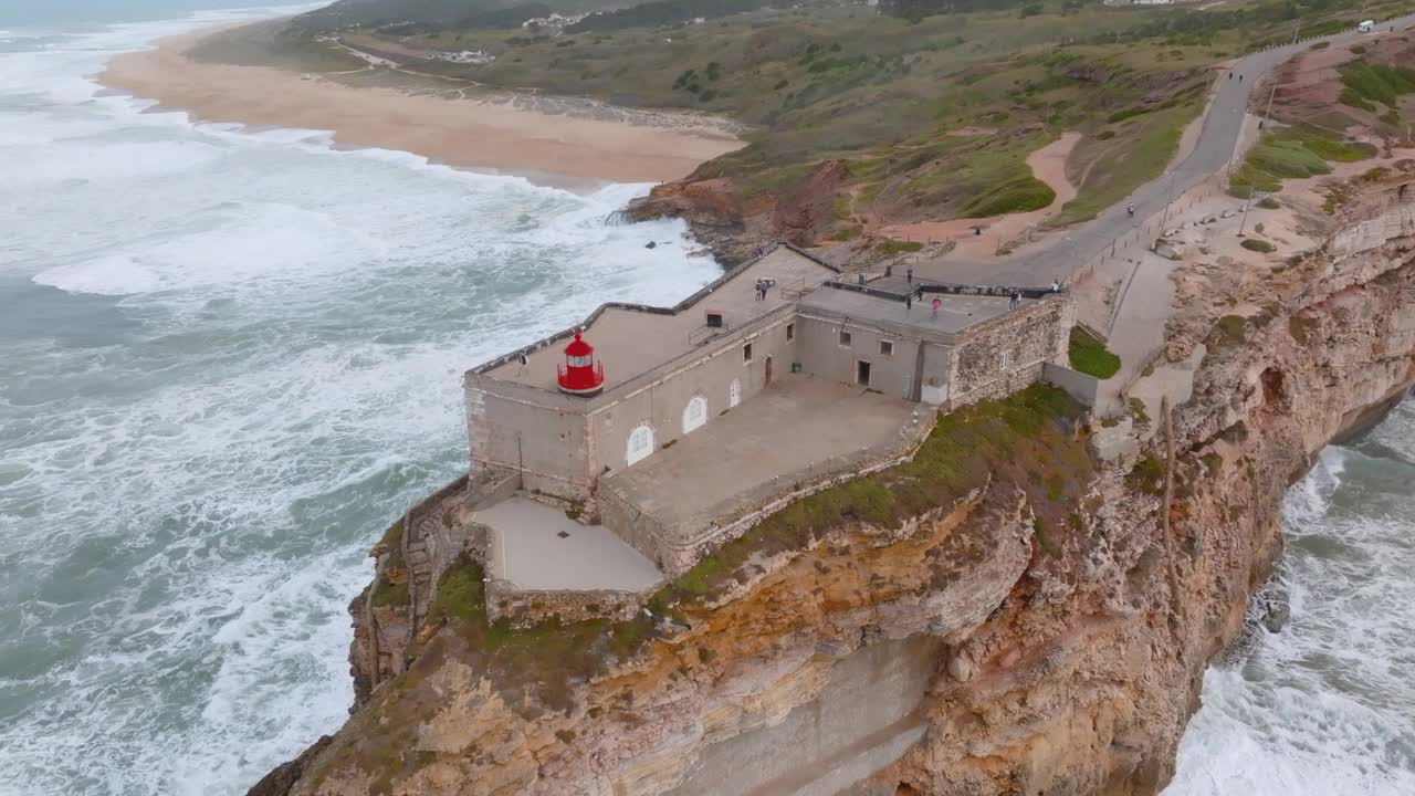 令人惊叹的鸟瞰图，圣米格尔堡的灯塔和大西洋海浪在葡萄牙纳扎雷北部普拉亚的冲击。视频下载