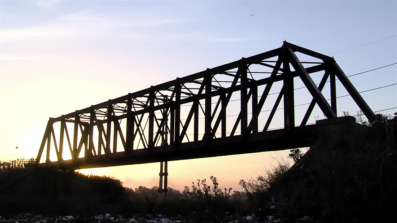 日落时分的老铁路桥，位于阿根廷布宜诺斯艾利斯省拉普拉塔市的“Barrio Puente de Fierro”(铁桥社区)。视频素材