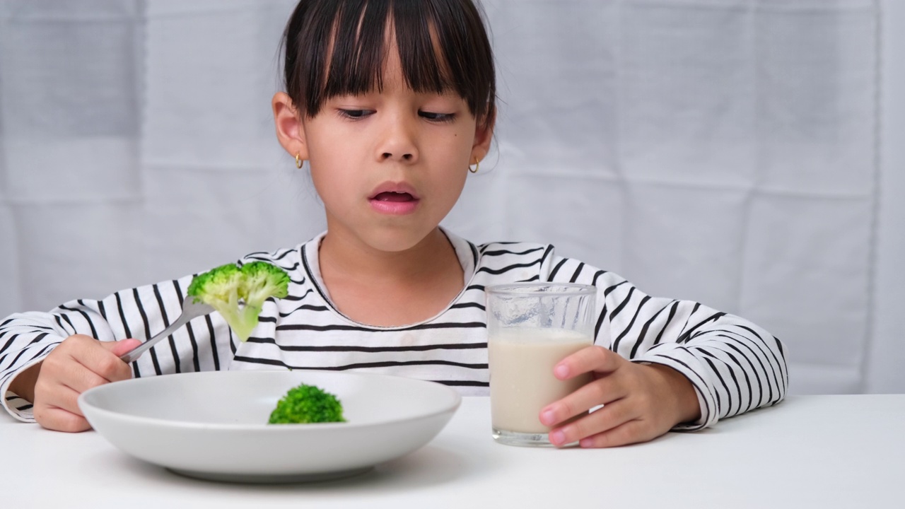 孩子们不喜欢吃蔬菜。可爱的亚洲女孩拒绝吃健康蔬菜。儿童的营养和健康饮食习惯。视频素材