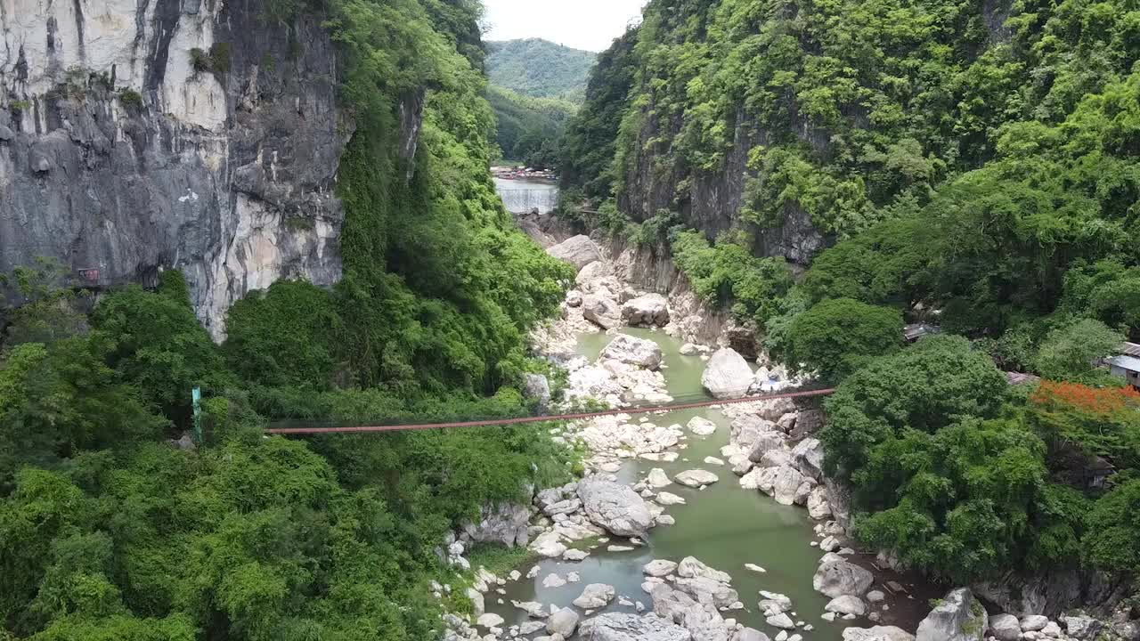 沿着茂密的森林，有石头和岩石的小溪上的无人机镜头视频素材